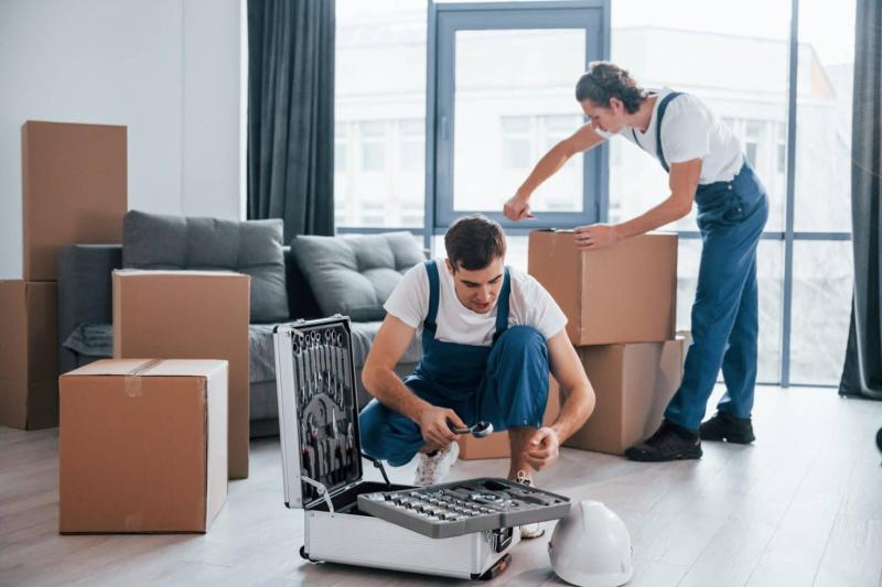 two-young-movers-in-blue-uniform-working-indoors-in-the-room