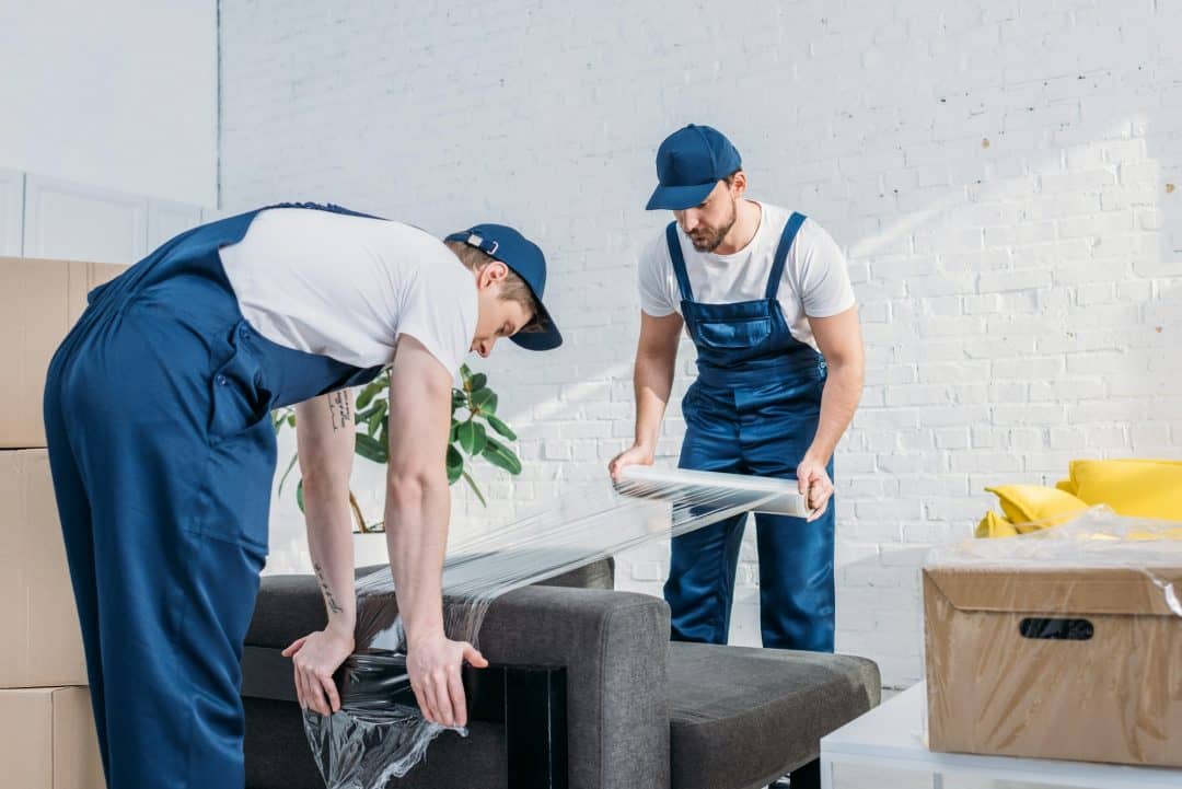 movers-wrapping-couch-with-roll-of-stretch-film-in-apartment